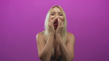 Yeşil dantelli sutyen giyen sarışın kadın mor stüdyoda el hareketleriyle seni çağırıyor..