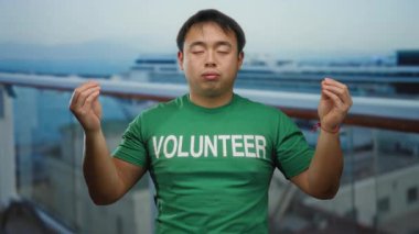 Bir yolcu gemisinde meditasyon yapan Asyalı bir adam açık havada gönüllü bir gömlek giyiyor, gözleri huzurlu bir şekilde kapalı seyahat ve hizmet ile farkındalığı karıştırıyor..