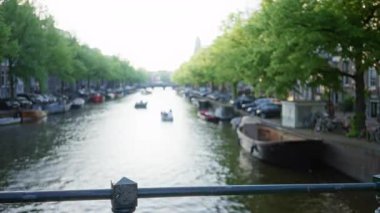 Amsterdam 'da sakin bir kanal. Sanatsal bir efekt için bulanık bir odak noktası yakalamış kayıklar ve sudaki yemyeşil ağaçlar..