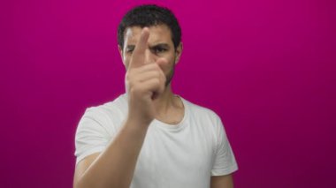 Stüdyoda pembe arka planda kararlı bir ifadeyle kamerayı işaret eden adam..