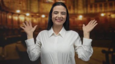 Ilık bir kilisenin içinde sevinçle gülümseyen genç İspanyol kadın beyaz bir gömlek giyiyor, kolları açık coşku ve mutluluğu ifade ediyor..