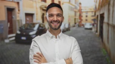 Eski bir kasaba şehrinin şehir sokağında kendine güvenle duran, sırıtan İspanyol bir adam açık havada beyaz bir gömlek giyerek şehir geçmişini gözler önüne seriyor..