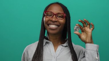 Elinde ethereum para tutan kadın yeşil arka planda gülümsüyor, kripto para birimi coşkusu sergiliyor ve pozitif ifade engelleme teknolojisini destekliyor..