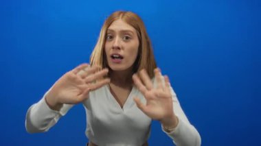 Genç sarışın kadın stüdyoda birini işaret etmek için el sallıyor..