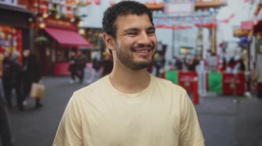 Gündüz vakti işlek bir şehirde sarı bir tişört giyen genç adam görünür dudaklarla gülümsüyor. Mutluluk..