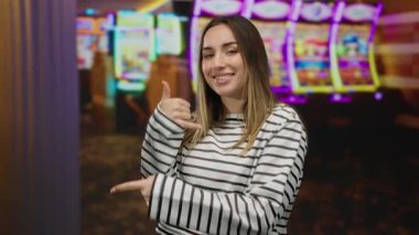 Çizgili tişörtlü genç bir kadın, arka planda kumar makineleri olan canlı bir kumarhanede neşeli ve canlı bir atmosferi içeri taşır..