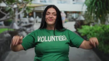 Kentin dışında yeşil tişörtlü bir kadın gönüllü olarak çalışıyor. Sokakta güvenle dikiliyor ve pozitif ruhunu gözler önüne seriyor..