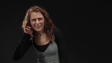 Siyah bir arkaplan üzerine merakını dile getiren kadın neşeli bir jest ile duygularını ve iletişimini izole bir ortamda vurguluyor..