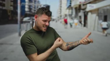Dövmeli genç adam canlı bir şehir sokağında halat çekerken neşeli ifadesini ve dövmeli kollarını bulanık şehir geçmişine gösteriyor..