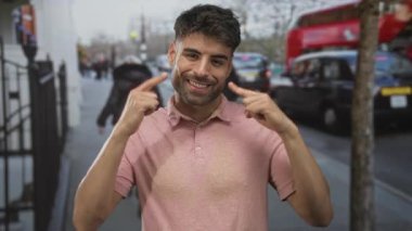 Adam, kalabalık şehir caddesinde arabaları ve yayaları ile geniş bir gülümseme ile parmak yanağa dolaşırken; mutluluk.