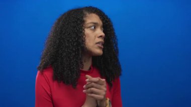 Mavi stüdyoda elleri sımsıkı bağlı Afrika kökenli Amerikalı bir kadın. Endişeli bir ifadeyle gözleri kapalı..