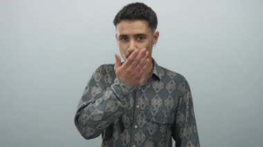 Genç İspanyol bir adam kameraya doğru bir öpücük yolluyor beyaz izole bir arka plan duvarına karşı desenli bir gömlek giyiyor..