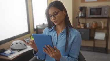 Bir kadının, modern bir iş ortamında tabletle ofis ortamında yoğunlaşması verimliliği ve odaklanmayı öneriyor..