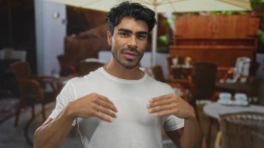 Güneşli bir restoran terasında saç şekillendirme ve beyaz gömlek yaka ayarlama erkek; özgüven kolaylıkla tımar.