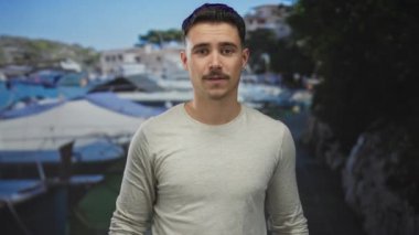 Şehir merkezindeki bulanık geçmişi olan Latin kökenli genç adam açık mavi gökyüzü altında davetkar bir jest sergiliyor.