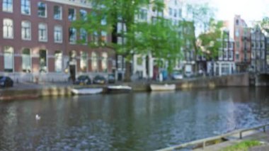Amsterdam 'ın ikonik kanallarının bulanık binalar ve teknelerle bulanık görüntüsü, Hollanda kentlerinin özünü barışçıl bir ortamda yakalıyor..