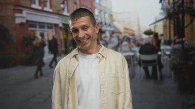 Canlı şehir caddesinde arka planda şehir manzarası ve günlük hayatı sergileyen insanlarla birlikte sıradan gömlekli beyaz bir adam..
