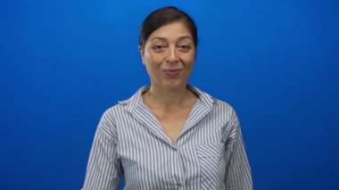 Mavi stüdyoda sessizlik için dudaktan dudaklara İspanyol kadın parmakları odaklı çizgili gömlek giyerek sakin ol..