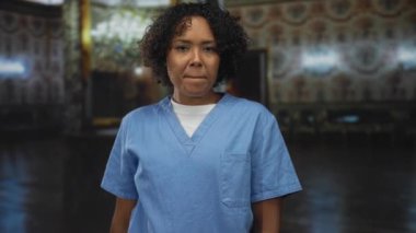 Mavi önlük giyen kadın, müze binasında sert bakışlarla, meydan okumayla yumruğunu seyirciye doğrultuyor..