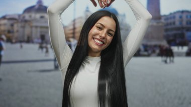 Beyaz elbiseli kadın, Vatikan 'da mutluluğu gösteren St. Peter Meydanı' nda elleri havada kalp hareketi yapıyor..