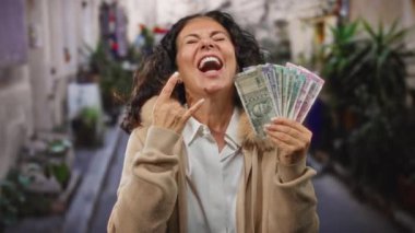 Elinde Hint rupileri tutan bir kadın hareketli bir şehir caddesinde kaya jesti yapıyor. Canlı bir şehir manzarası yakalıyor..