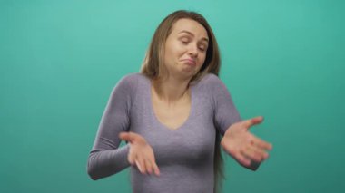 Yeşil arka planda omuz silkerek kafa karışıklığını ifade eden bir kadın, kararsızlık ya da belirsizliği işaret ediyor..