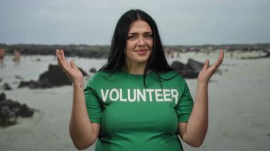 Yeşil gömlekli, deniz kenarında gönüllü olarak çalışan genç bir kadın, açık deniz çevresi ve deniz altyapısından hoşlanıyor. Toplumun katılımını ve doğa korumasını teşvik ediyor..