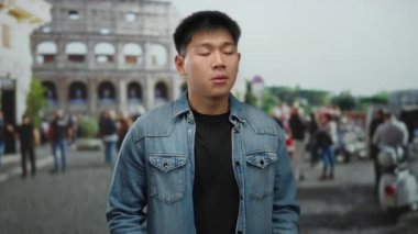 Genç Çinli adam, şehir caddesinde Roma Kolezyumu 'nun önünde ellerini uzatarak modern modayla tarihi mimariyi ve canlı şehir yaşamını harmanlıyor..