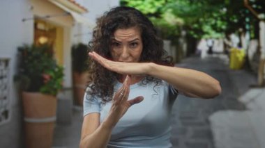 Kadın, güneşli bir şehir caddesinde ellerini göğsünün önüne kaldırarak mola veriyor. Kendine güven sınırı var..