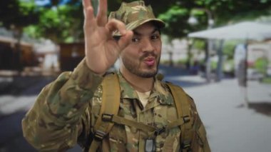 Askeri üniformalı genç İspanyol, şehir caddesinde elle imza atıyor..