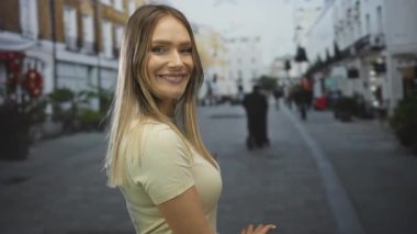 Kalabalık bir şehir caddesinde kollarını açmış gülümseyen bir kadın binalar ve arka planda insanlar olan canlı şehir atmosferini gösteriyor..