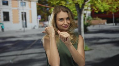 Yeşil elbiseli, kentsel sokak ortamında gülümseyen bir kadın güneşli bir şehir arka planında neşeli ve neşeli davranışlar sergiliyor..