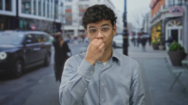 Genç İspanyol adam sessiz kalmak için parmaklarını hareket ettirdi şehir caddesinde bulanık yayalar ve taksiyle; sessiz gizem.