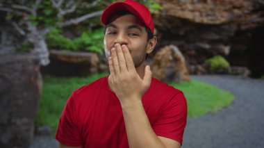 Kırmızı şapkalı ve gömlekli gülümseyen genç İspanyol bir adam ormanda el pençe divan öpüşen dudaklara; şefkat bağı sıcaklığı.