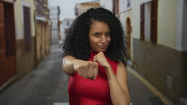 Gündüz vakti dar bir sokakta yumruklarını kaldırmış kırmızı üst üste boks yapan gülümseyen kadın, kişisel yetki..