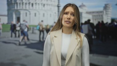 Kadın, şehir hayatı ve turizmi vurgulayan hareketli bir sokak sahnesinde beyaz bir kadının yer aldığı sidik kulesinin yakınındaki açık hava gürültüsünün ortasında kulaklarını kapatıyor..