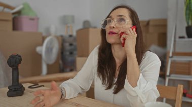 Telefonla konuşan bir kadın yeni evdeki kutuları taşırken evin içinde yoğun bir geçiş olduğunu düşündüren aletler etrafa saçılmış..