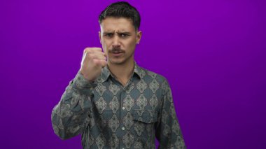 Genç adam, güçlü duygular ve kararlılıkla, canlı, mor duvarlara karşı duygularını ifade ediyor. Gömlek ve izole bir arkaplan sergiliyor.