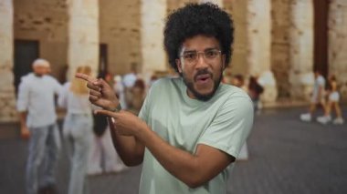 Bulanık arka planı olan, şehir atmosferini vurgulayan, çeşitli, neşeli ifadeler sergileyen bir adam heyecanlı bir şekilde dışarıyı işaret ediyor..