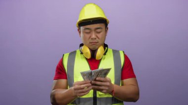 Mor arka planda güvenlik yeleği ve başlık takarak dolar sayan inşaat işçisi, münferit odaklı endüstriyel ya da finansal bağlamda