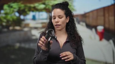 Güneşli bir caddede spor yapan bir kadın yeşil ve günlük kıyafetlerle spor yapıyor, fitness odaklı şehir ortamında odak ve kararlılık gösteriyor..