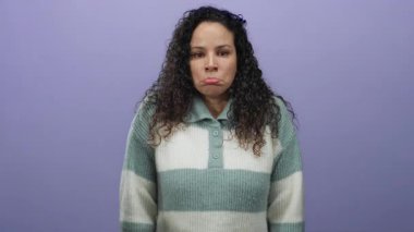 Çizgili kazaklı kıvırcık saçlı kadın, mor duvara karşı üzgün görünüyor. Stüdyoda tek başına melankolik duygularını ifade ediyor. Yalnızlık ve tefekkür hissi uyandırıyor..