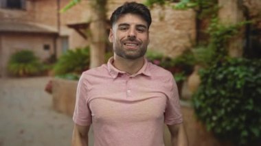 Güneşli eski şehir sokağında taş bina cepheleri ve saksı yeşilliği ile kaplanmış insan çerçeveleri; neşe.