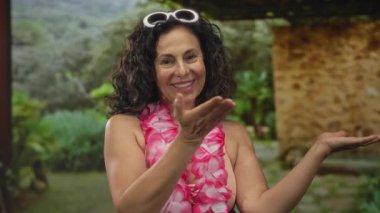 Bikinili ve çiçekli kadın parkta çıplak kollarını uzatarak jest yapıyor..