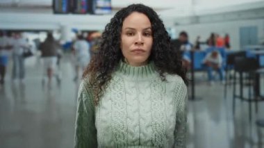 Havaalanı terminalindeki kadın, yeşil, kıvırcık saçlı, İspanyol kökenli, gezginlerle dolup taşan bir kazak giydiğine şaşırdı..