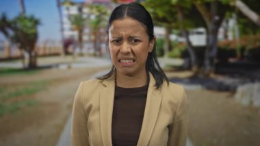 İspanyol kadın parkta yeşillik ve arka planda ağaçlardan tiksinerek doğal elementleri ve duygusal ifadeyi yansıtan canlı bir açık hava sahnesi yaratıyor..