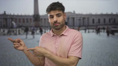 Pembe polo giyen genç İspanyol adam tarihi bina avlusundaki Dikilitaş 'ı işaret ediyor..