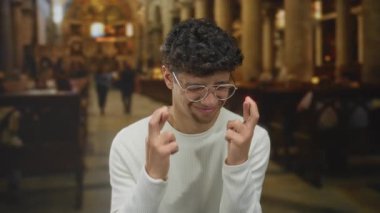 Süslü kilise binası, vitray pencereleri ve mermer sütunları olan ahşap bankta dua eden bir adam..