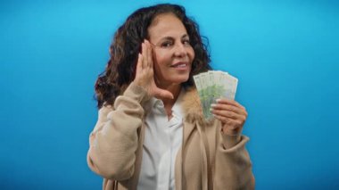 Orta yaşlı bir kadın gülümsüyor ve elinde Romen banknotları tutuyordu. Mutluluk ve finansal başarıyı soyutlanmış neşeli bir ifadeyle aktarıyordu..