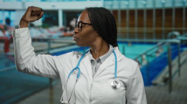 Laboratuvar önlüğü ve steteskop giyen bir kadın havuz kenarında duruyor ve dışarıda tıbbi bir ortamda profesyonelliği ön plana çıkarıyor..
